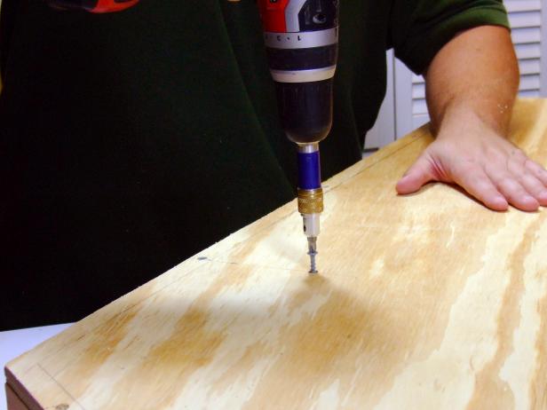 Drill a countersunk pilot hole at 4 inches from edge on this line and drive a 2" screw through the bottom and into the support block assembly.