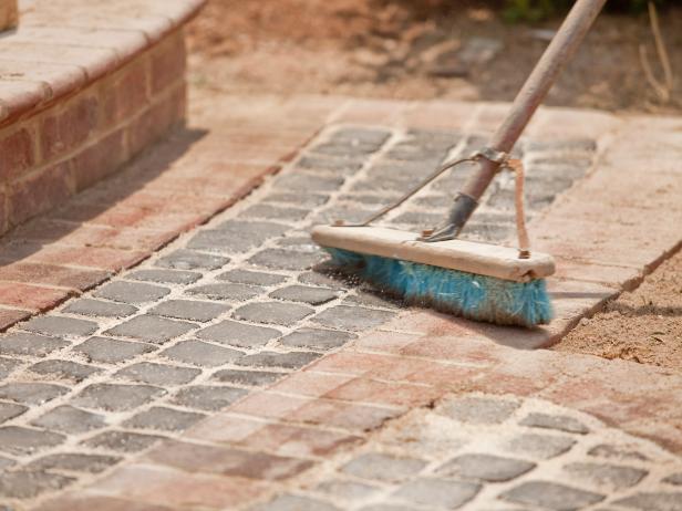 Use a push broom to sweep the excess grout from atop the stones. Sweep the stone-covered area clean.