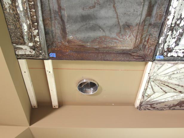 To accommodate ceiling lights, ceiling vents, fan boxes and smoke alarms, measure carefully and, with tin snips, hand-cut openings in tin panels to ensure a snug fit.