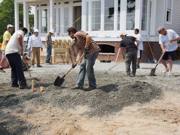 Drive grading stakes into the ground and use a 6' level and string line to keep the grade consistent. You can also rent a laser level and tripod, which will cost you about $50 per day. This is a more advanced and accurate method for determining grade.