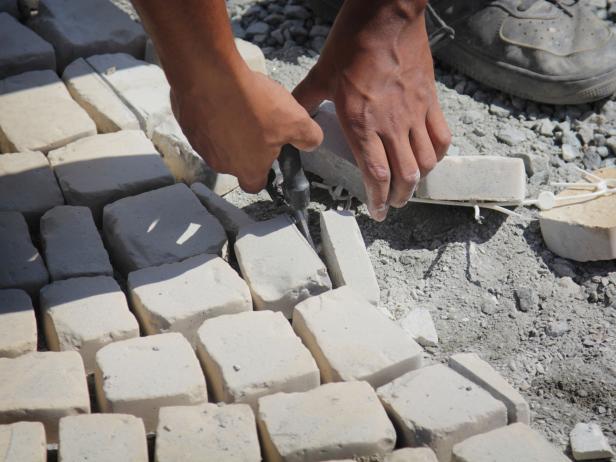 After using a concrete cut-off saw to cut the edge of your patio, use snips to remove the excess stone on the outside of the perimeter.