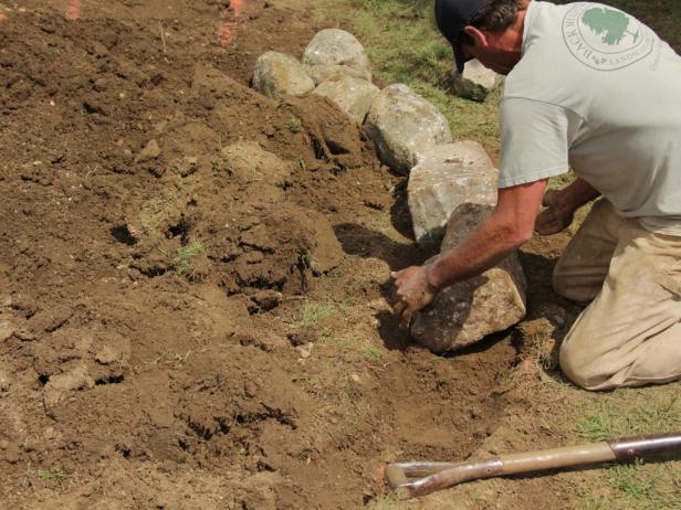 Lay the large stone first around the perimeter of the raised bed.