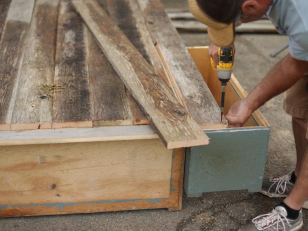After attaching the middle board to the back of the cabinet, attach the remaining boards so they are flush at each end of the outer cabinets.