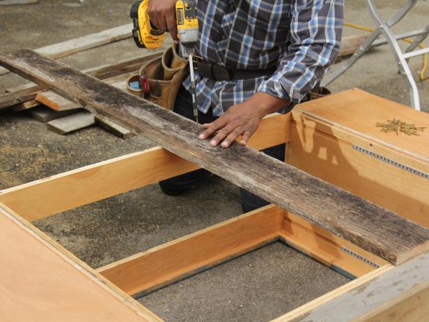 Place first board in the center of the middle cabinet. Attach the middle of the board to the back of the cabinet with one screw. Then, using a framing square, ensure board is perpendicular to the cabinet before driving a second screw in board at the bottom.