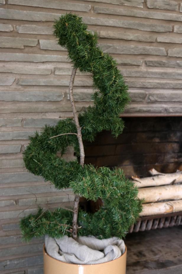 Make an all-season spiral topiary using a branch and faux evergreen.