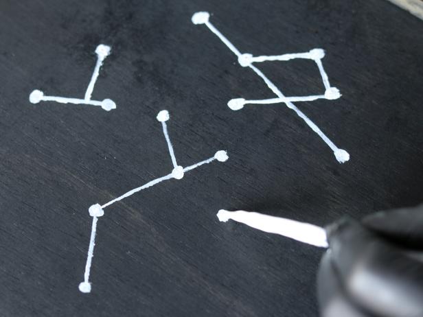 Use detail paint brush and white semi-gloss paint to create the look of constellations. This can be freehanded and random or done literally in reference to an actual star chart.