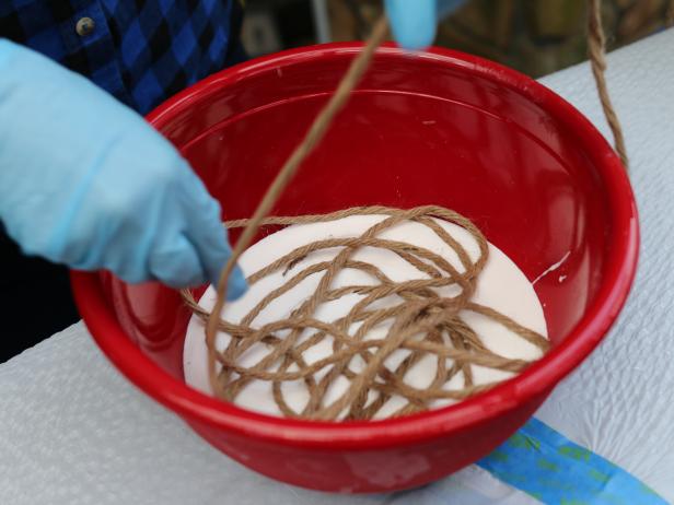 Protect your hands with rubber gloves. Unfurl spool of sisal rope, then slowly submerge it into the decoupage glue. Move the rope around, ensuring all sides are evenly covered.