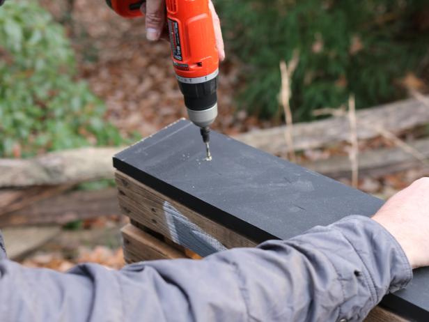 Use drill and 2â exterior wood screws to fasten the two shorter trim pieces to the sides of the pallet.