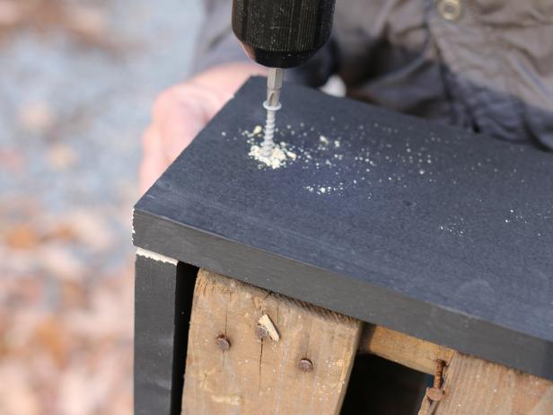 Once the two smaller trim pieces are secure, use drill to secure the longer trim pieces to the pallet, slightly overlapping the others to create perfect edges.