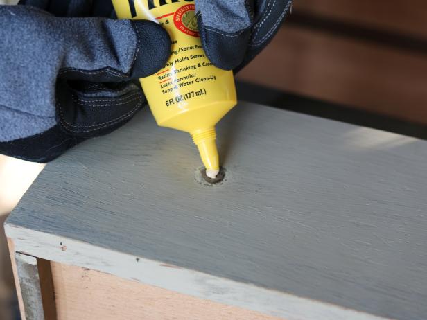 New hardware will be attached to the drawer fronts, and therefore new holes will need to be drilled. Fill the holes with wood filler, then smooth the surface using a spackle knife.