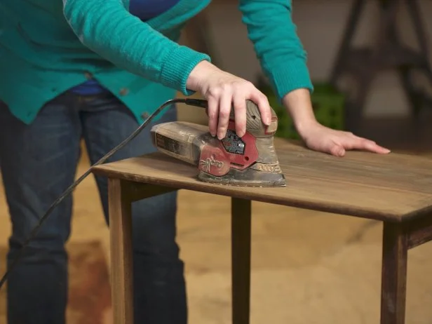 To remove those last bits of finish, palm sand with medium sandpaper (150 grit) until you see the bare wood. Then switch to fine sandpaper (200+ grit) until the entire piece is uniform. Wipe down the whole surface with a tack cloth to remove any dust from sanding.