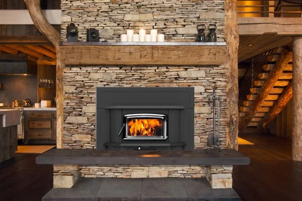 Woodburning Stove in Stone Fireplace A wood-burning insert can increase the efficiency and heating capacity of a fireplace while emitting less pollution.