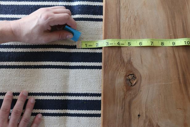 Place the cushion directly onto the flat weave rug. Use chalk to outline the chair cushion directly to the rug, allowing an additional 2 ½ inches all the way around to account for wrapping along the edges.