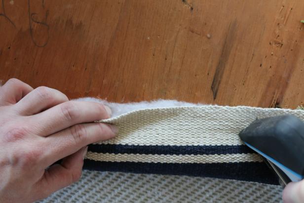 With the help of a friend, stretch the rug cutout over the seat cushion and onto its back. Secure in place using staple gun.