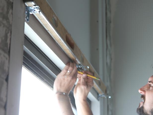 Place the level on top of the two mounted brackets. Hold the center bracket in place and mark the bracket holes. Repeat steps 3 and 4 to mount the center bracket.