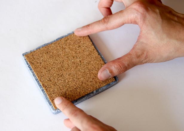 Attach adhesive cork to back of ceramic tile. The cork will prevent the coaster from scratching your furniture.