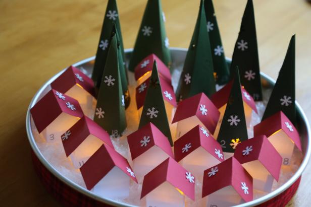 The Completed Paper Advent Village is Illuminated The tray is filled with twenty-four trees and houses that are glowing.