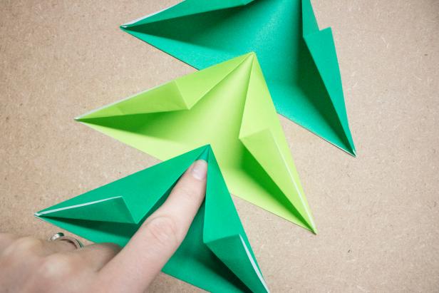 Fold paper Christmas trees and top with origami stars for Christmas-themed decor.
