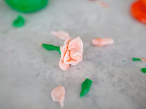 Tear off small, even pieces of fondant to make the rose center and petals. You'll need about 16 pieces for each rose. Using wax paper or parchment paper, flatten out the pieces and thin out the edges.