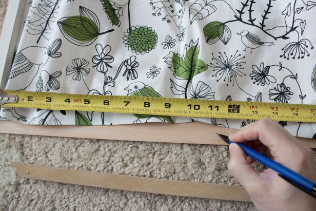 DIY bedside book organizer using plywood, trim, and fabric.