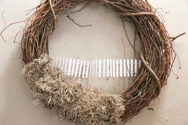 Attach the Fence to the Fairy Wreath A white picket fence is attached to the wreath.