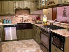 A kitchen that has been renovated into a French country space with new distressed cabinets, granite countertops, backsplash, flooring, copper sink, and appliances. Part of the wall has been removed to open the space.