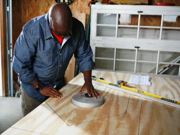 Man traces around circular item to make a door opening for the doghouse.