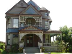 Queen anne home and porch design with arched architectural details and blue and red colors. 