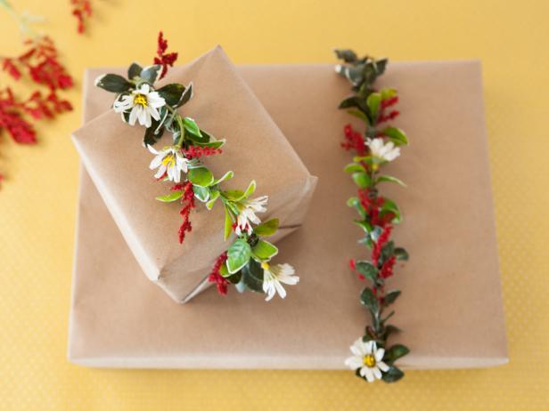 Christmas presents wrapped in floral garland aranged in a photo.