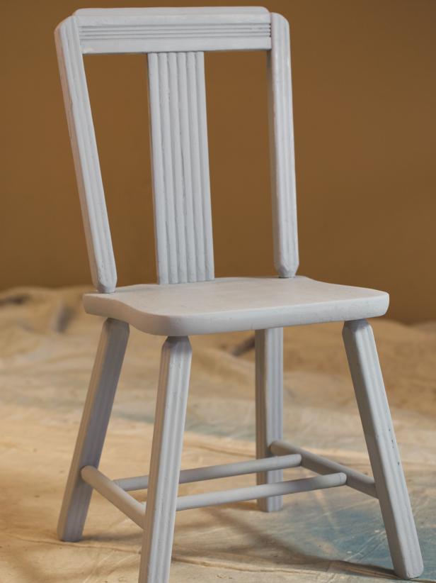 Use a spray primer for neat, even coverage. Choose a white primer under light colors and a darker primer under darker colors for uniform coverage. Begin with the underside of the chair. Spray slowly for a consistent spray pattern to avoid drips and overspray. Use a back and forth motion following the natural lines of the chair. Apply 2-3 light coats, allowing primer to dry to the touch between each application. Check your primer label because drying times vary widely. If surface feels a little coarse once the final coat is dry, lightly sand with very fine sandpaper and wipe again with a tack cloth to remove dust.