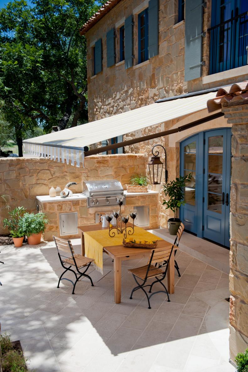 Dine al fresco underneath an awning, such as this one made with Sunbrella fabric for a Texas home. The built-in grill and storage back up to a sandstone wall in the intimate courtyard space. 