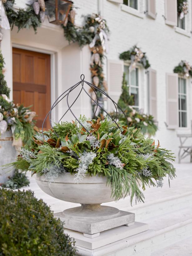 Winter Container with fresh greenery and trellis on grand porch of French Country home