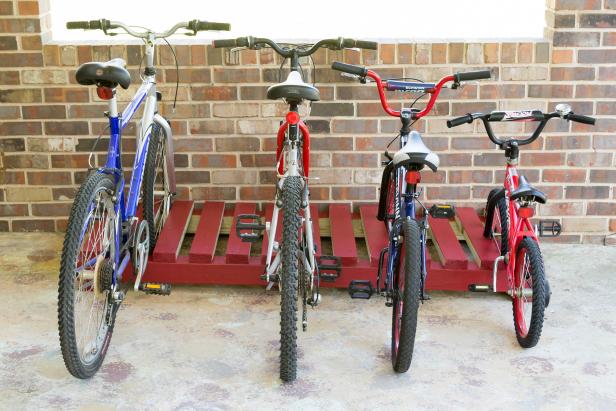 bikes lined up on a red wooded bike rack.