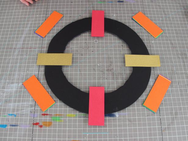 Using the double stick tape, affix the red and gold strips at the 12, 3, 6 and 9 positions on a clock face.