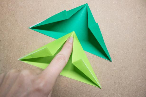 Fold paper Christmas trees and top with origami stars for Christmas-themed decor.