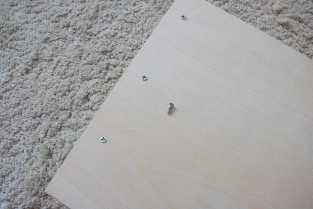 DIY bedside book organizer using plywood, trim, and fabric.