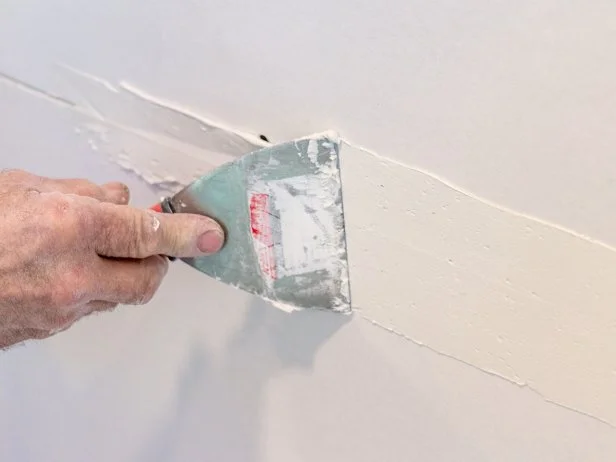 Use a 4" putty knife to fill the drywall seam from one end to the other. You'll be working in thin coats. Be patient!