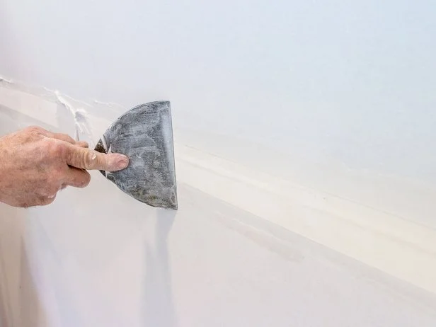 Use a 6" drywall knife to spread a thin layer of joint compound (mud) over the tape and surrounding area.