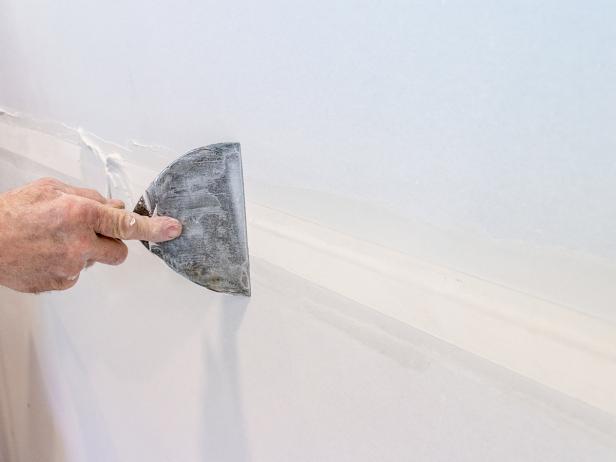 Use a 6" drywall knife to spread a thin layer of joint compound (mud) over the tape and surrounding area.