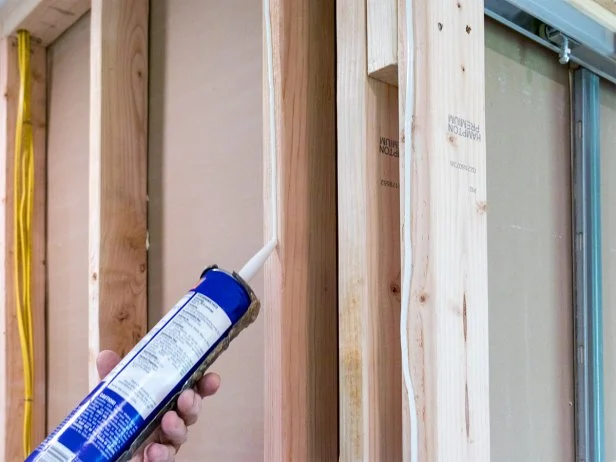 Apply adhesive to the studs that will be behind your drywall. This helps you use fewer screws, and it also provides sound insulation.