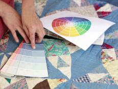 Sharon Kaye choosing a color by matching up the paint book with a quilt in the room.